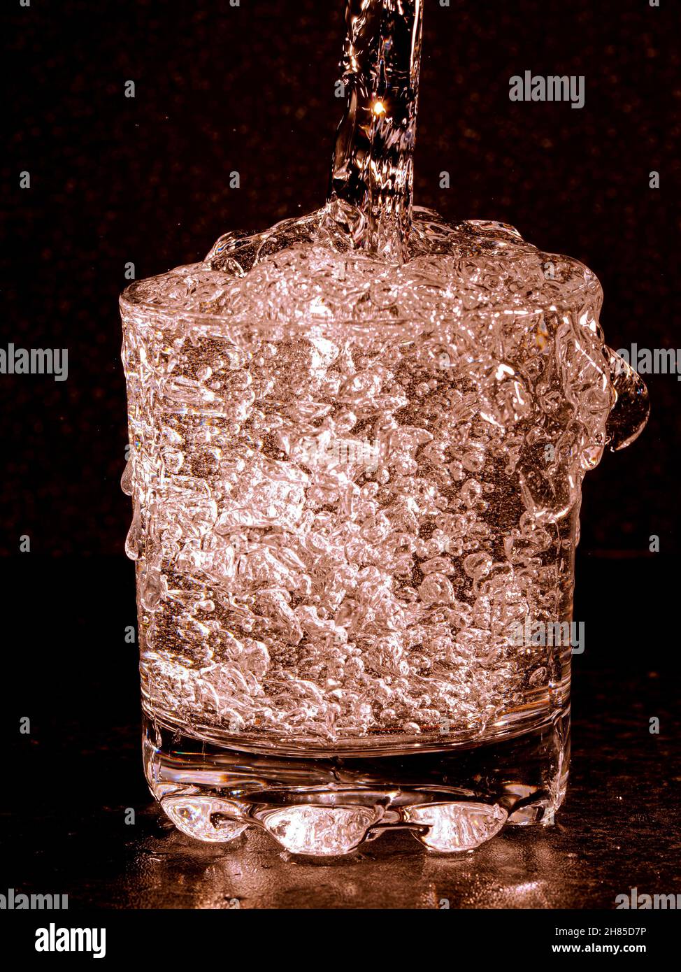 Spruzzare acqua versando nel vetro con delle bolle Foto Stock