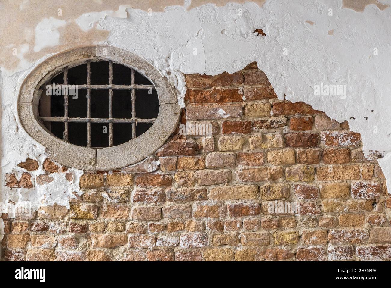 Mattone e dipinto Stucco muro con una vecchia finestra rotonda, Foto Stock