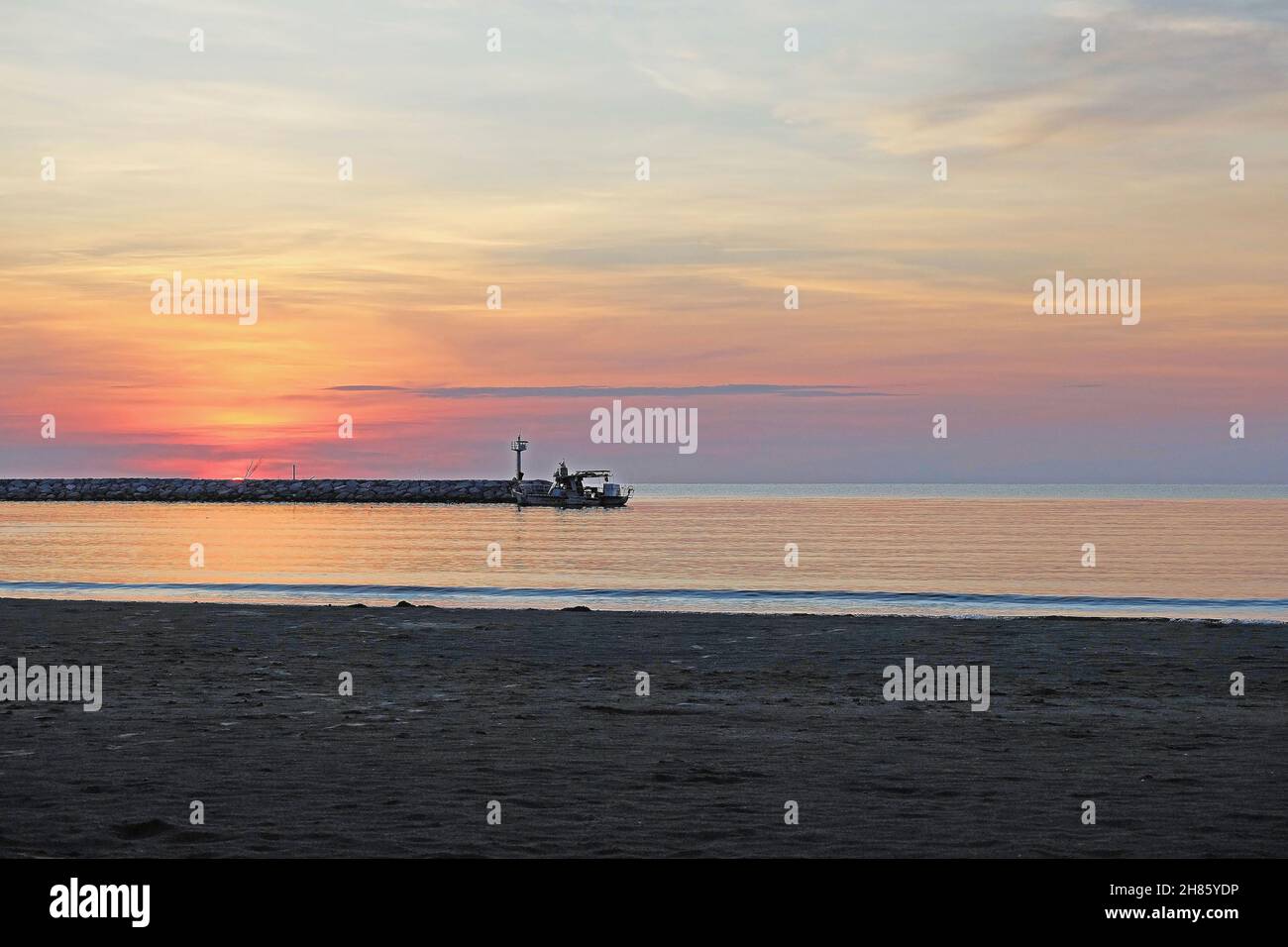 Texture di spiaggia di sabbia, superficie di acqua di mare e cielo su luci cremisi all'alba Foto Stock