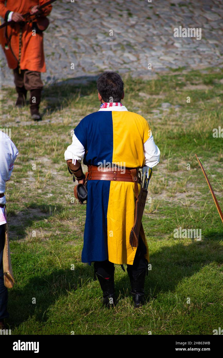 Persone in abiti medievali con archi sul territorio del castello Foto Stock