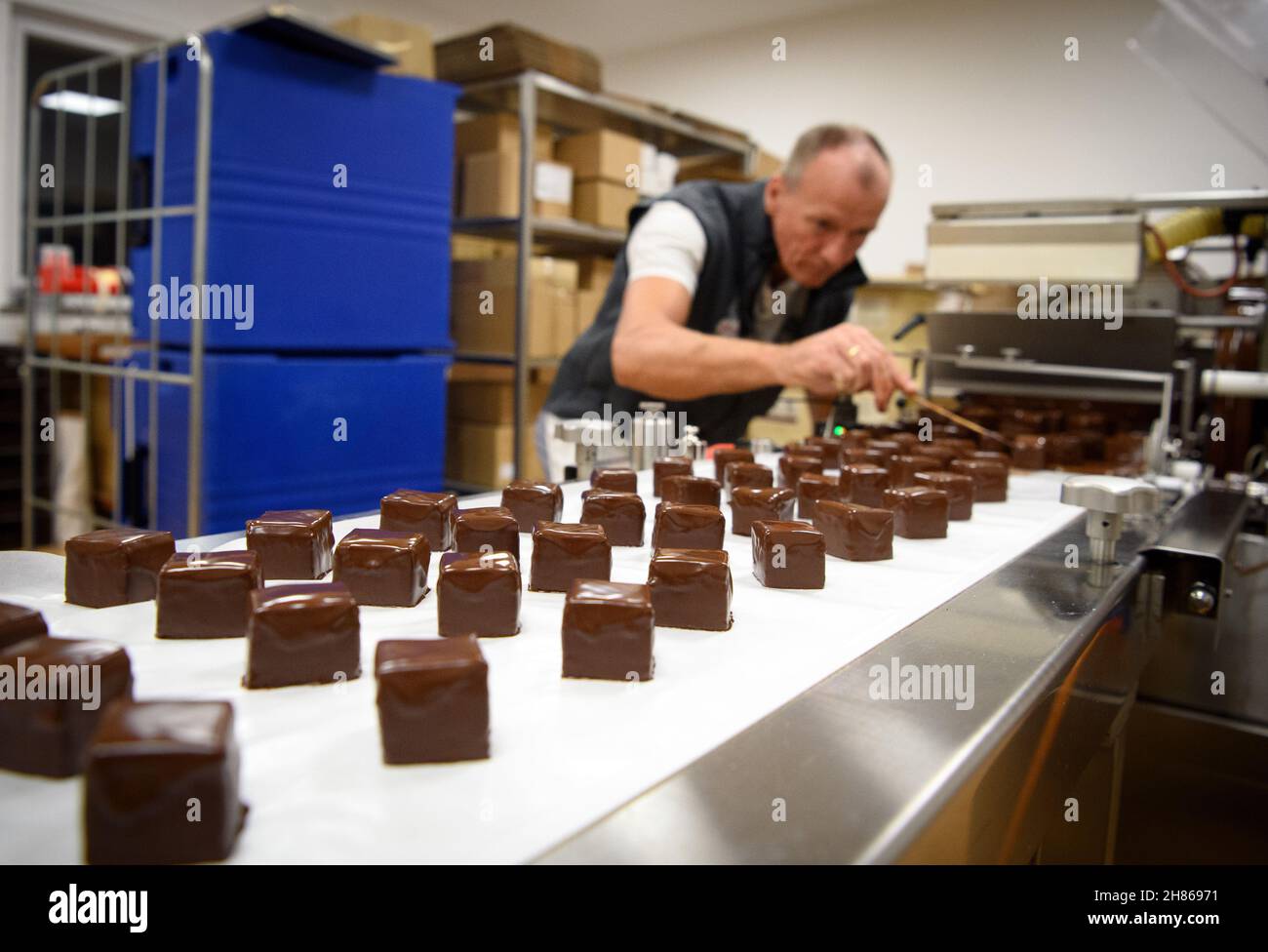 22 novembre 2021, Brandeburgo, Oberkrämer/OT Schwante: La pasticciera Torsten Dieckmann controlla le dominelle finite nella panetteria e pasticceria Plentz dopo averle rivestite con cioccolato. Al momento, quasi tutto nel business della famiglia, che è stato fondato nel 1877, ruota intorno al commercio di Natale. Oltre al Stollen, i dominoes di Plentz sono molto popolari anche tra i clienti. (Al dpa 'Pre-Natale: Matrimonio nelle panetterie di Brandeburgo' dal 28.11.2021) Foto: Soeren Stache/dpa-Zentralbild/dpa Foto Stock