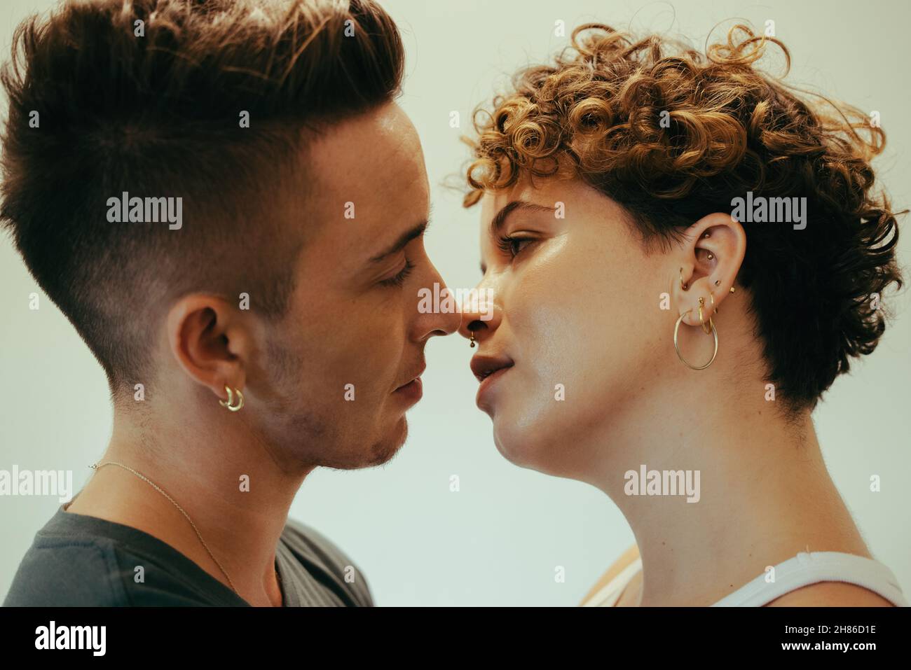 Coppia intima che va dentro per un bacio. Affettuoso giovane coppia queer in piedi l'uno vicino all'altro con gli occhi chiusi. Giovane coppia LGBTQ+ in condivisione Foto Stock