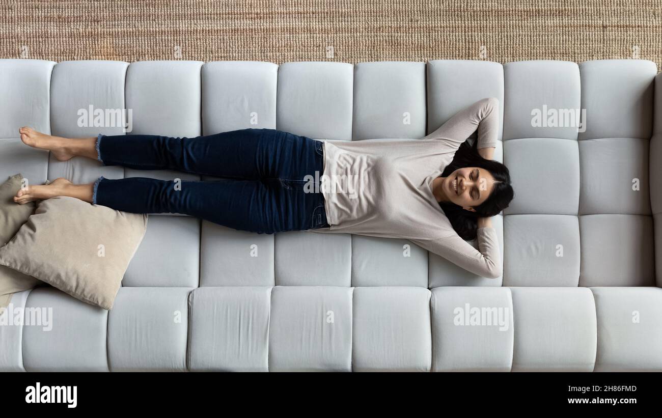 Sopra la vista sorridente donna asiatica relax su un comodo divano Foto Stock