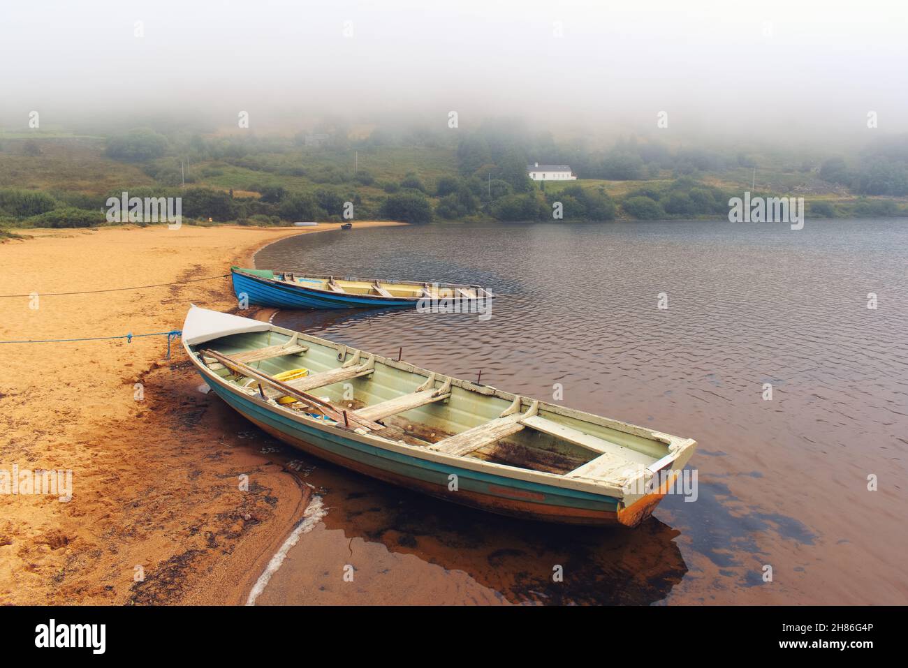 Bellissimo paesaggio mattutino con vecchia barca da pesca in legno sulla spiaggia sabbiosa di Loch Na Fooey nel parco nazionale di connemara nella contea di Galway, Irlanda Foto Stock