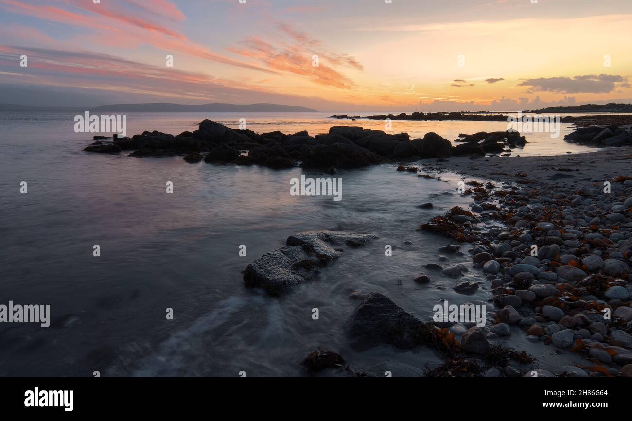 Splendido paesaggio marino al tramonto della costa rocciosa sulla strada atlantica selvaggia a Barna, Galway, Irlanda Foto Stock