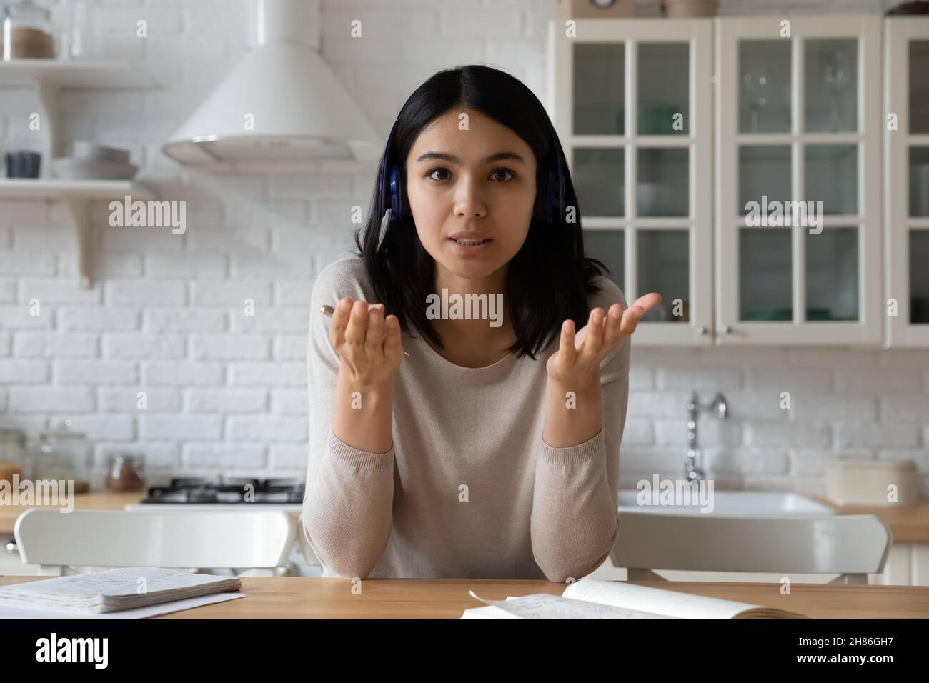 La donna asiatica in cuffia guarda la fotocamera che ha una conversazione con un videocall Foto Stock