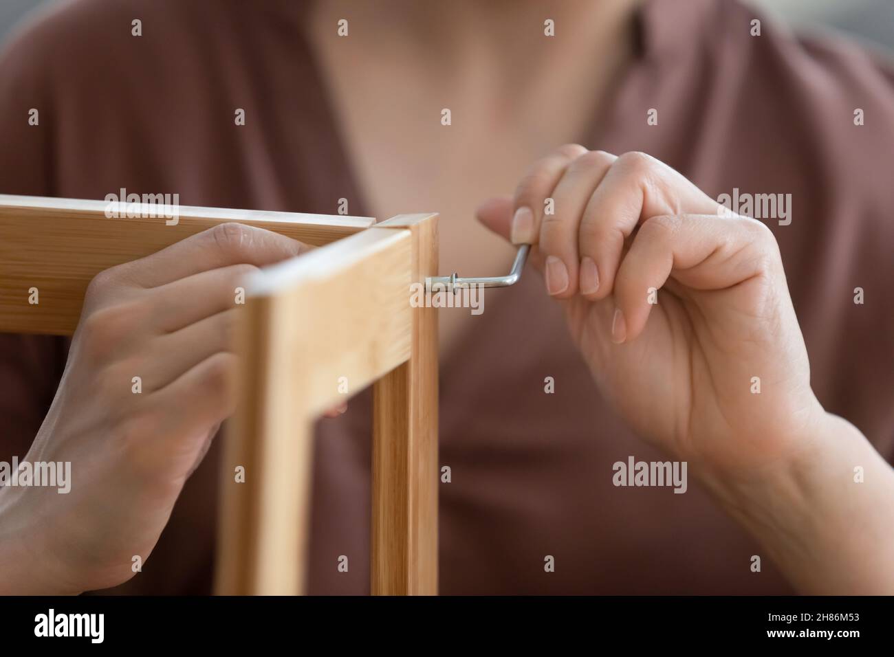 Primo piano giovane donna che monta mobili in legno a casa. Foto Stock
