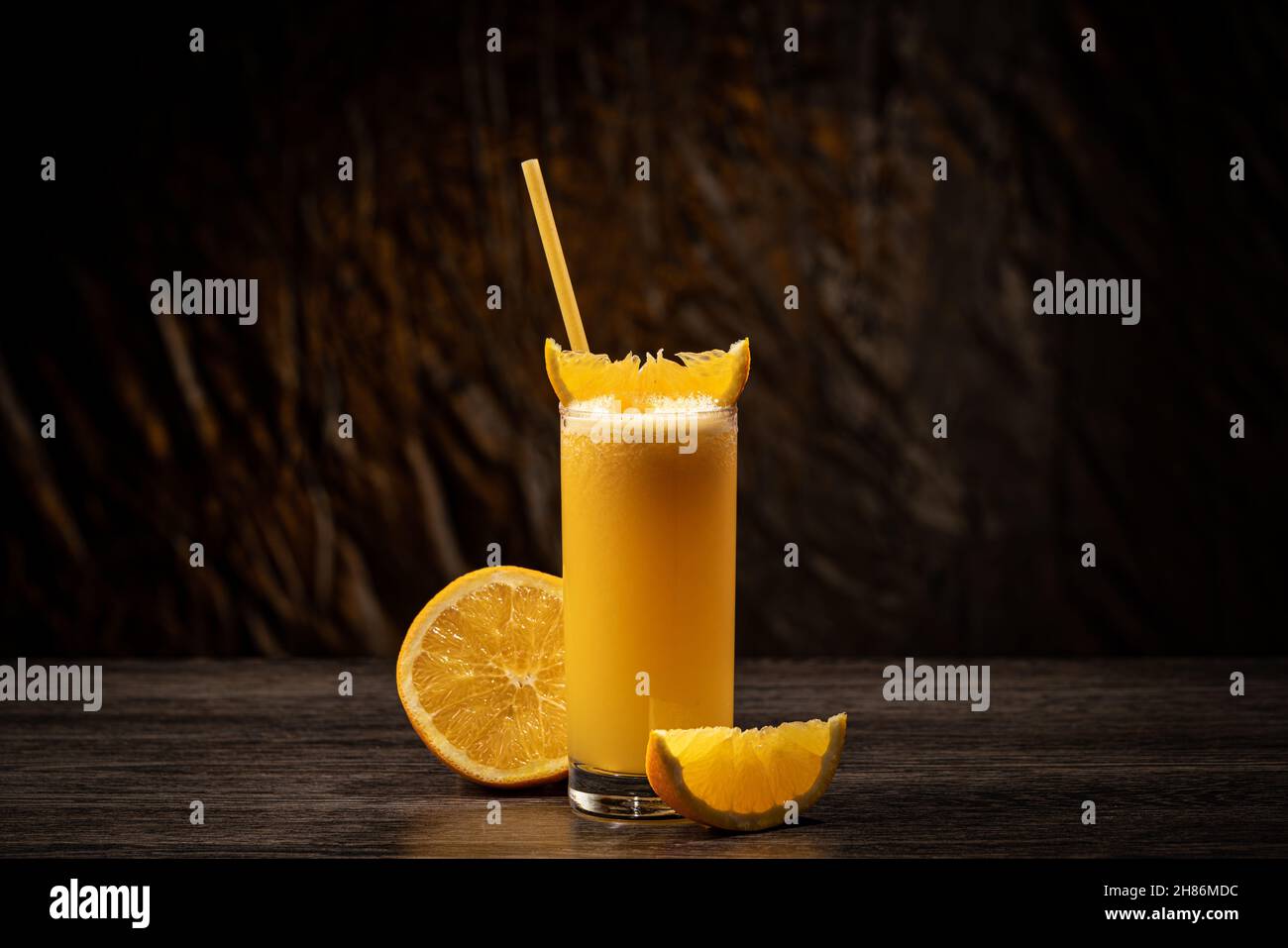 Bicchiere di succo d'arancia con frutta a fette su sfondo scuro Foto Stock