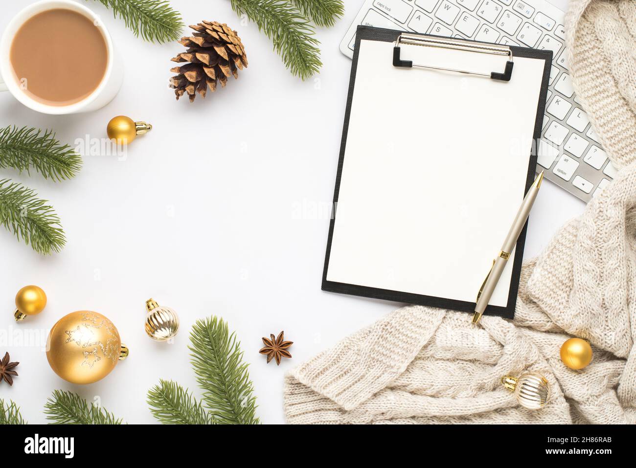 Vista dall'alto foto di appunti con foglio di carta penna tastiera tazza di caldo bere oro albero di natale palle pino ramoscelli cono anice e sciarpa a maglia su iso Foto Stock