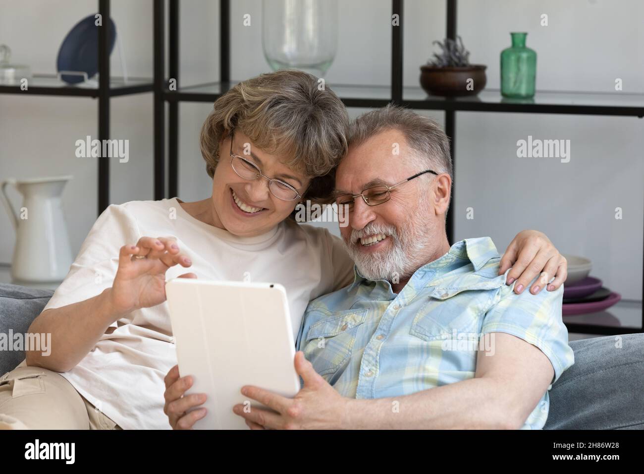 Coppia matura e allegra di pensionati che riposano sul divano a casa Foto Stock