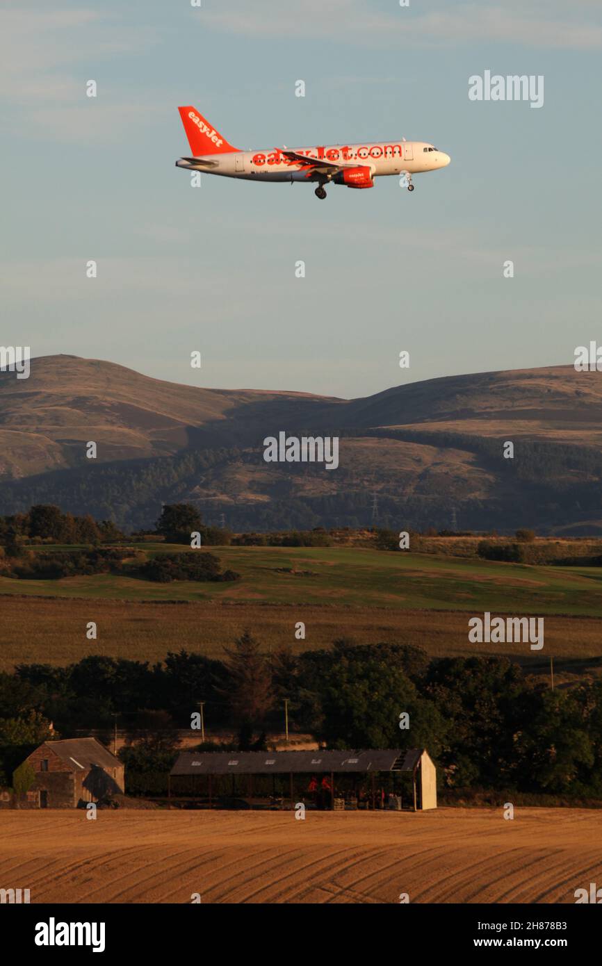 Con le colline del pentland sullo sfondo un aereo easyjet entra nell'aeroporto di Edimburgo illuminato dal sole della tarda sera Foto Stock