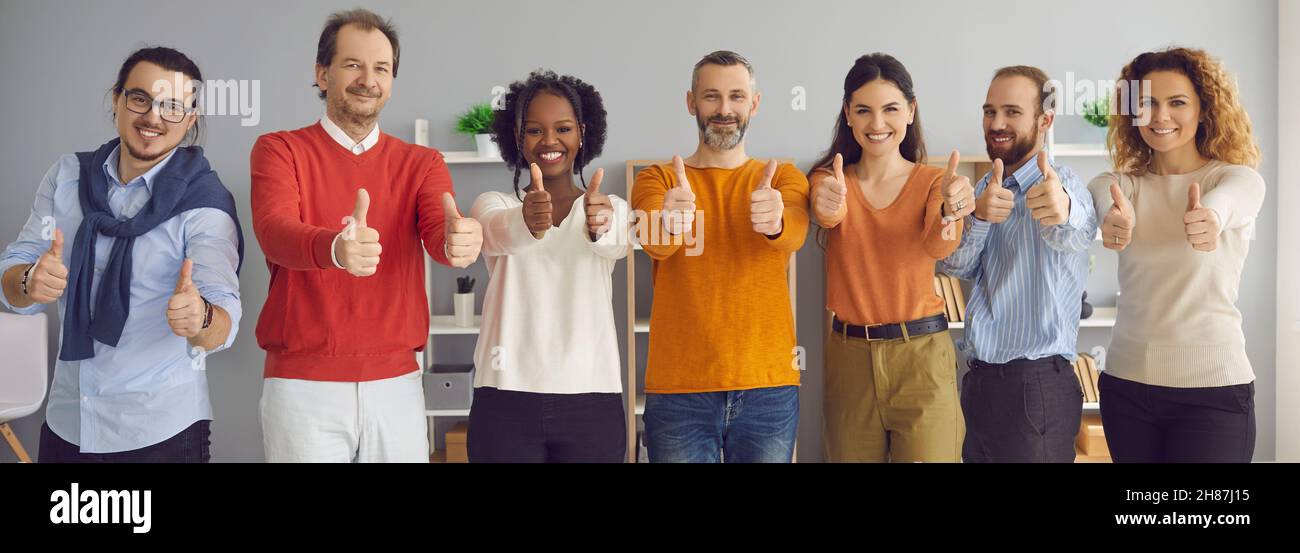 Felice sorridente gruppo di uomini d'affari che mostrano i pollici insieme alla fotocamera Foto Stock