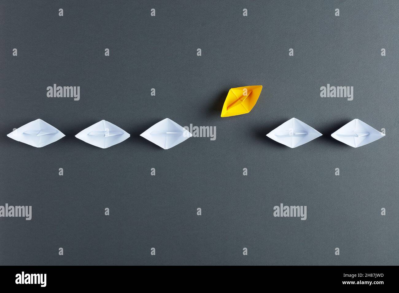 Barche di carta bianca in fila con una barca che va nella direzione differente. Individualità, differenza, creatività o improvvisazione nel business co Foto Stock