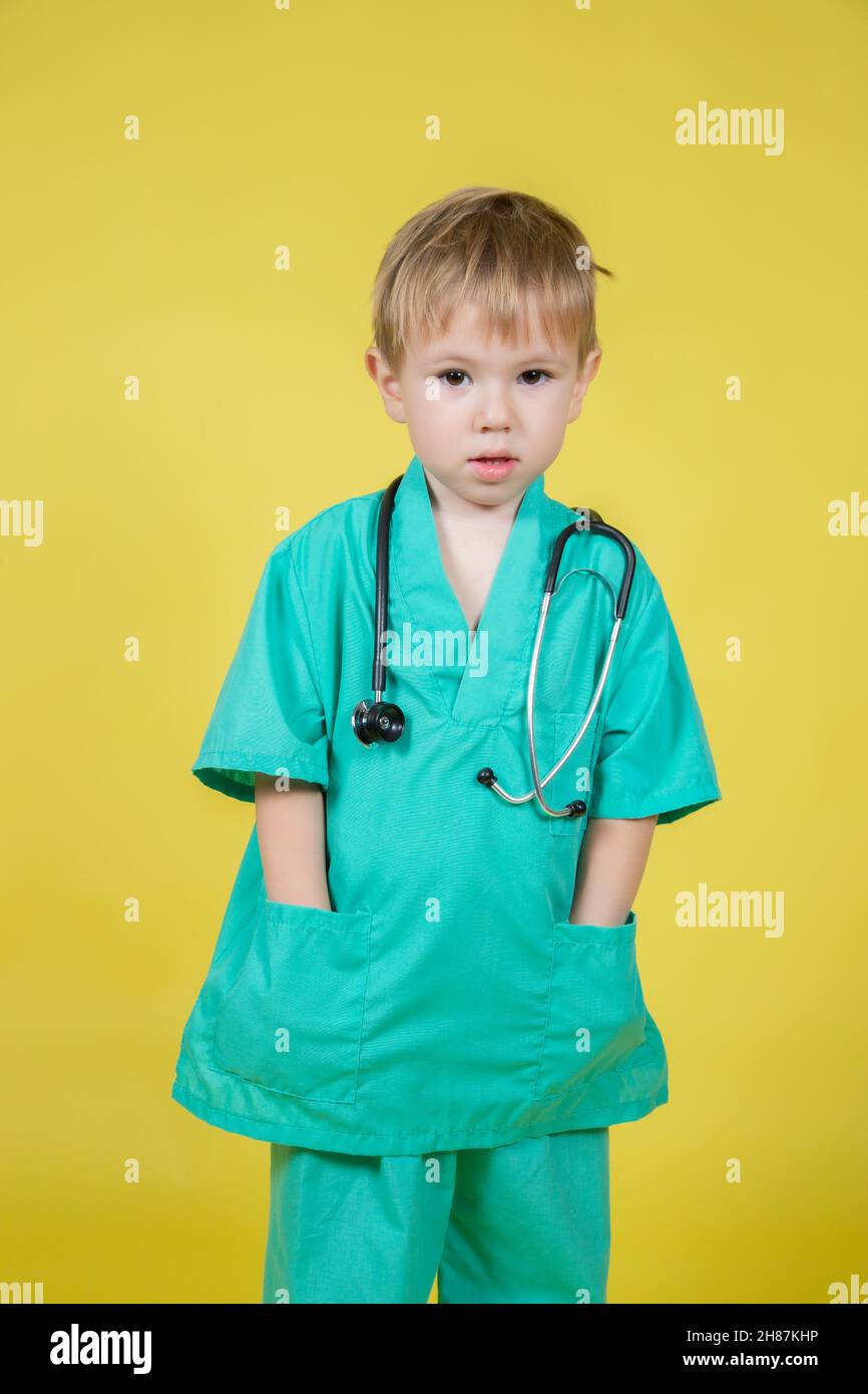 Ritratto di ragazzo caucasico vestito di dottori cappotto verde posa isolato su giallo Foto Stock