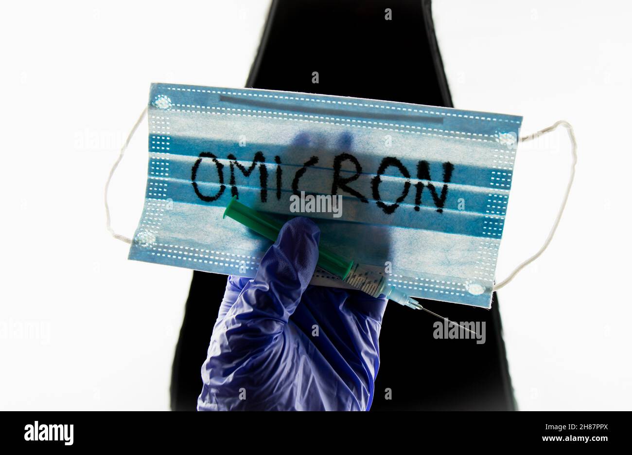 Nuovo concetto Omicron di mutazione di Coronavirus Covid-19. Maschera medica, siringa e testo con lettere Omicron. Foto Stock