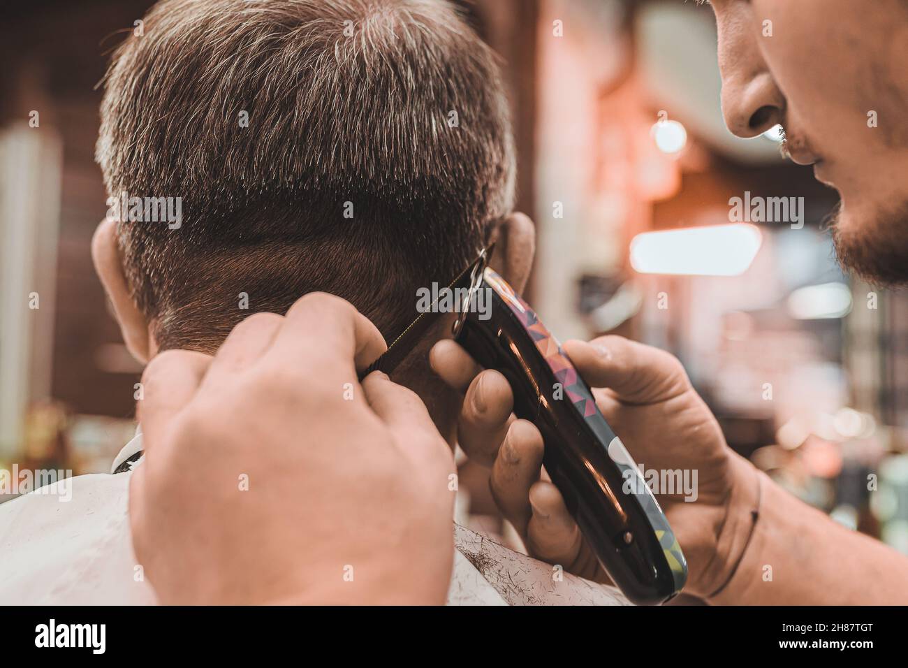 Barbiere. Parrucchiere esegue professionalmente un taglio per capelli per gli uomini. Uomo cliente siede in sedia professionale del barbiere e parrucchiere fa i capelli. Foto Stock