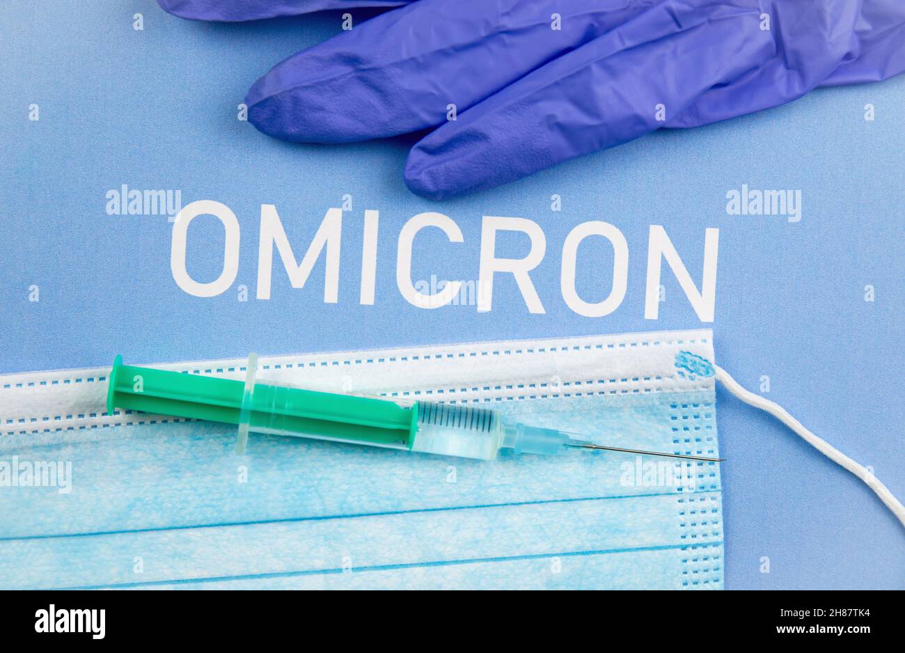 Nuovo concetto Omicron di mutazione di Coronavirus Covid-19. Maschera medica, siringa e testo con lettere Omicron. Foto Stock