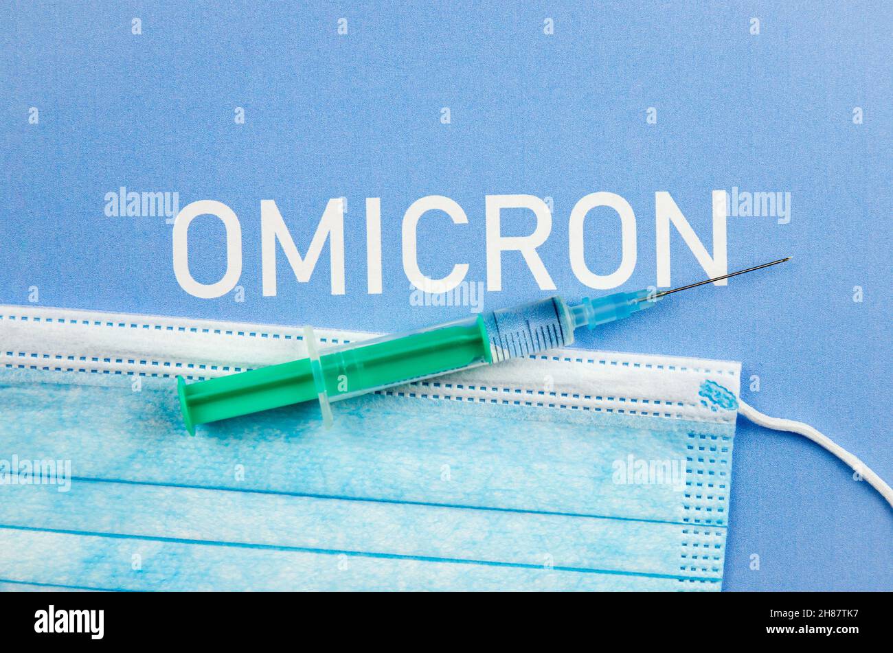 Nuovo concetto Omicron di mutazione di Coronavirus Covid-19. Maschera medica, siringa e testo con lettere Omicron. Foto Stock