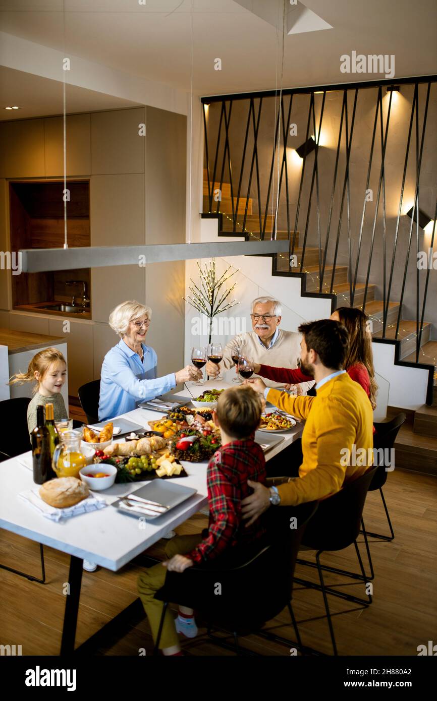 Famiglia felice che ha una cena con vino rosso a casa Foto Stock