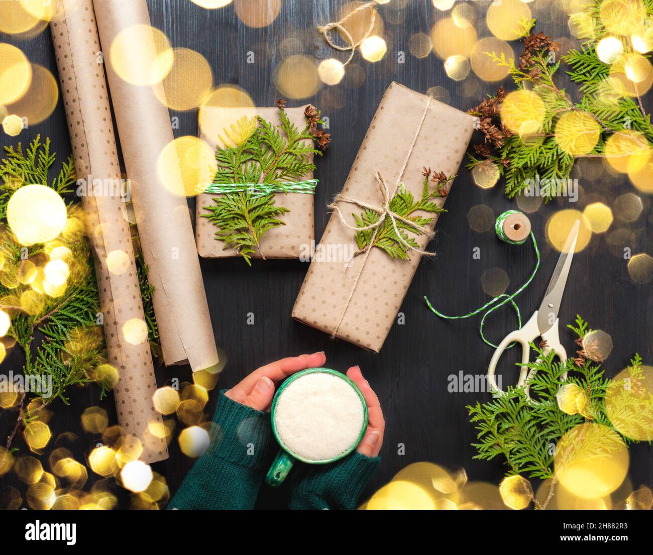 I regali di Natale avvolti in carta artigianale su sfondo scuro con luci di Natale Foto Stock