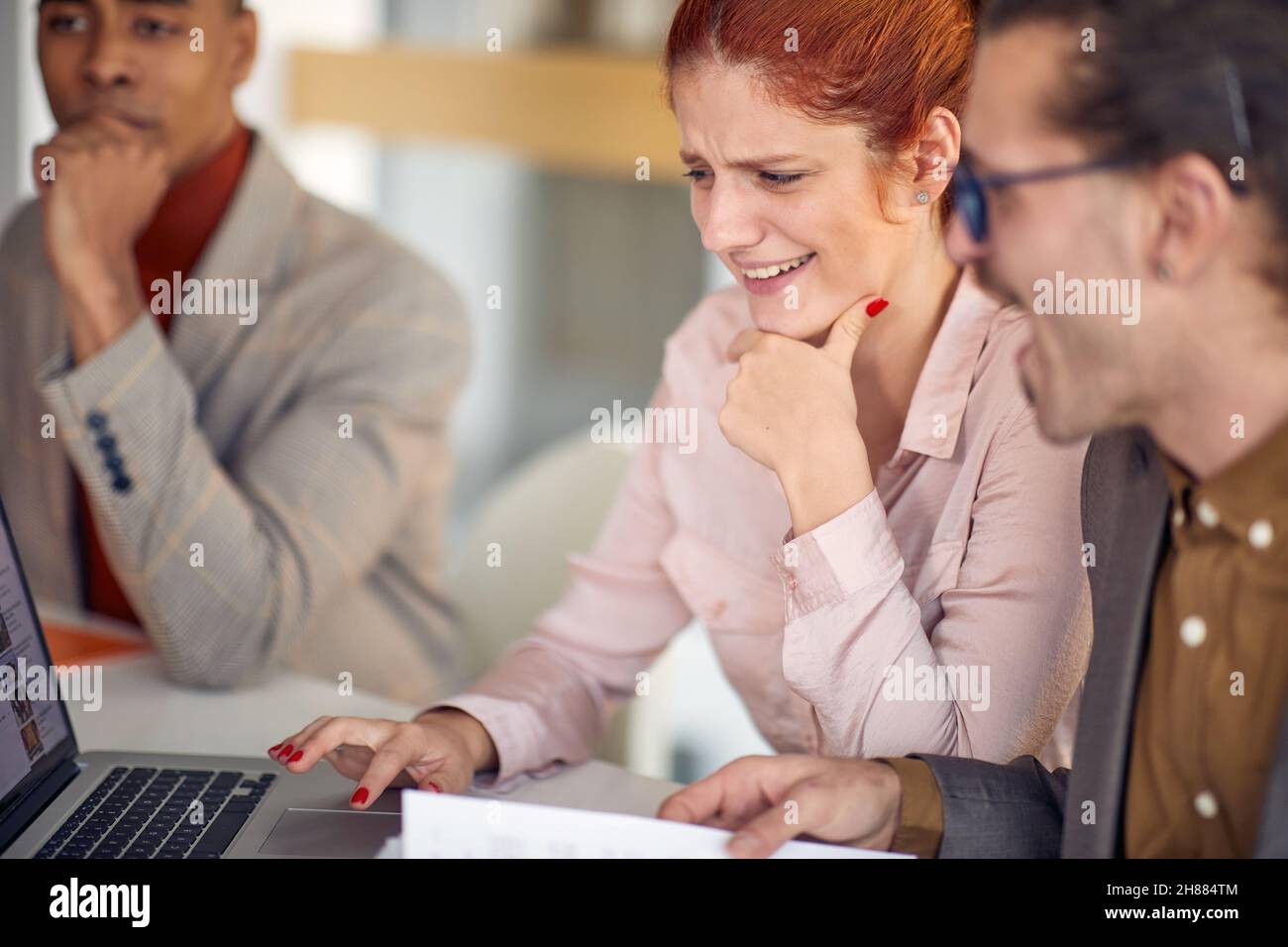 Due giovani colleghi seduti a guardare un contenuto di un notebook in un'atmosfera rilassata al lavoro. Aziende, persone, aziende Foto Stock