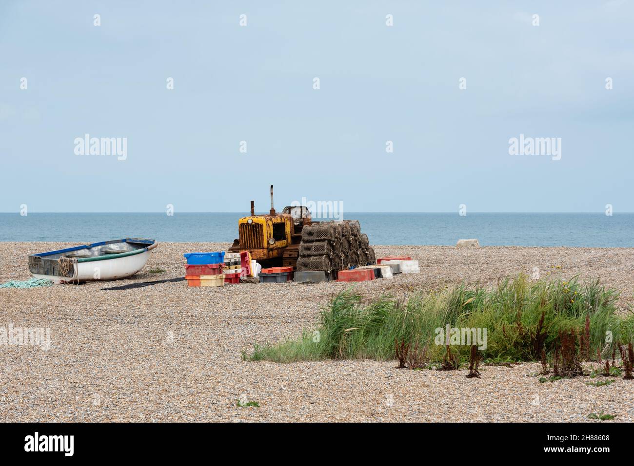 Spiaggia di ciottoli di Cley con barca da pesca, vasi di aragosta e trattore cingolato arrugginito. Agosto, 2021 Foto Stock