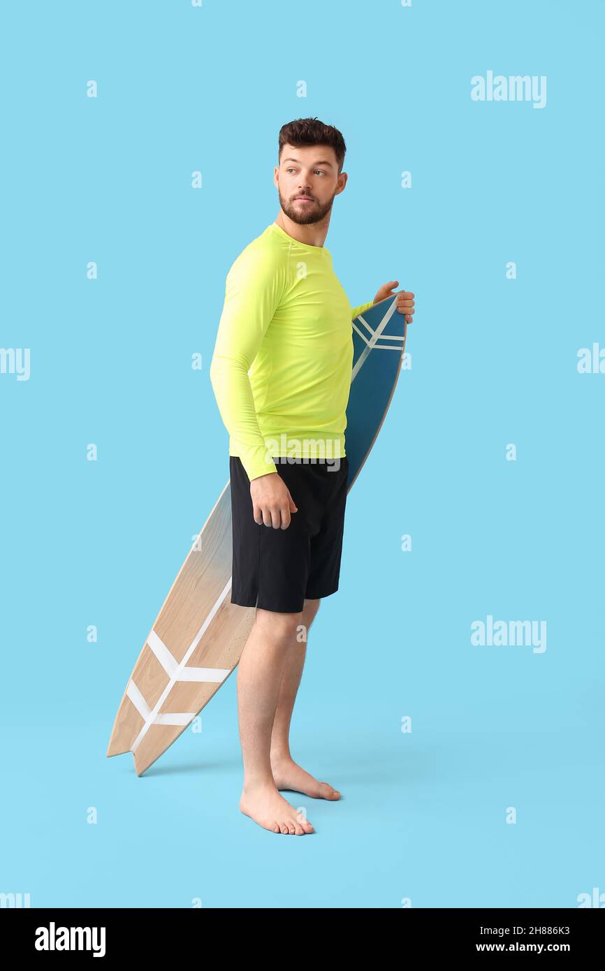 Bell'uomo barbuto con tavola da surf su sfondo blu Foto Stock