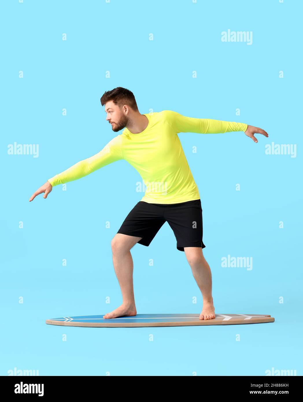 Bell'uomo barbuto con tavola da surf su sfondo blu Foto Stock