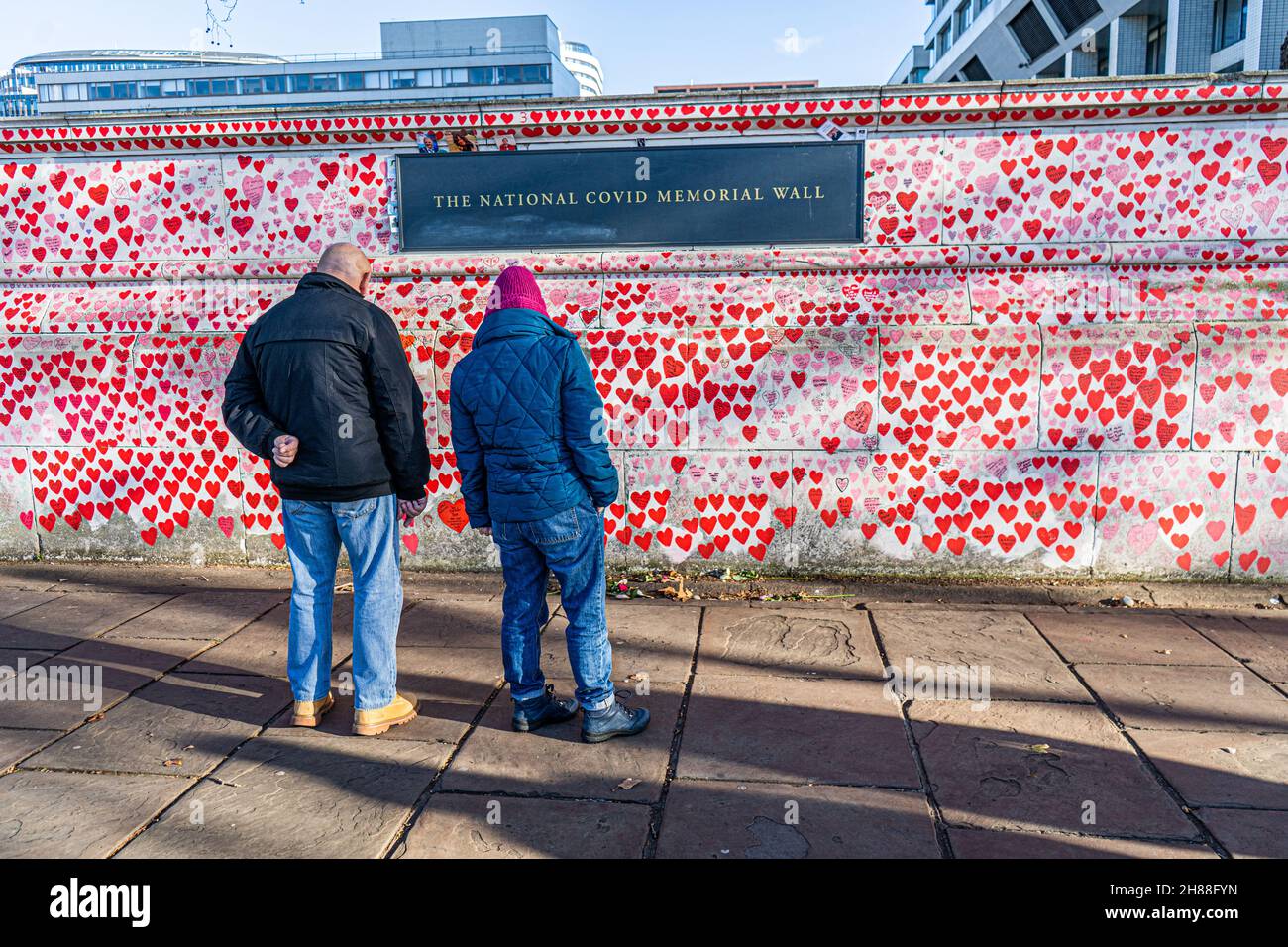 WESTMINSTER LONDRA, REGNO UNITO. 28 novembre 2021. La gente cammina oltre il muro del memoriale nazionale lungo il lungofiume del Tamigi in una luminosa domenica. Il governo ha annunciato misure più severe, tra cui l'obbligo di indossare maschere sui trasporti pubblici e nei negozi per fermare la diffusione della nuova variante sudafricana dopo che nel Regno Unito sono stati rilevati diversi casi del ceppo omicron. Credit: amer Ghazzal/Alamy Live News Foto Stock