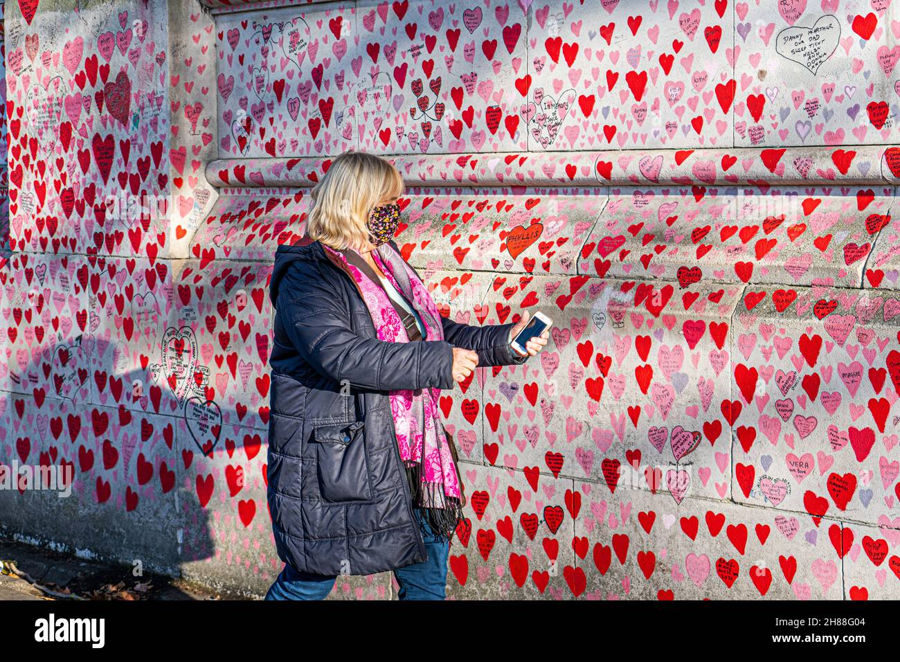 WESTMINSTER LONDRA, REGNO UNITO. 28 novembre 2021. La gente cammina oltre il muro del memoriale nazionale lungo il lungofiume del Tamigi in una luminosa domenica. Il governo ha annunciato misure più severe, tra cui l'obbligo di indossare maschere sui trasporti pubblici e nei negozi per fermare la diffusione della nuova variante sudafricana dopo che nel Regno Unito sono stati rilevati diversi casi del ceppo omicron. Credit: amer Ghazzal/Alamy Live News Foto Stock