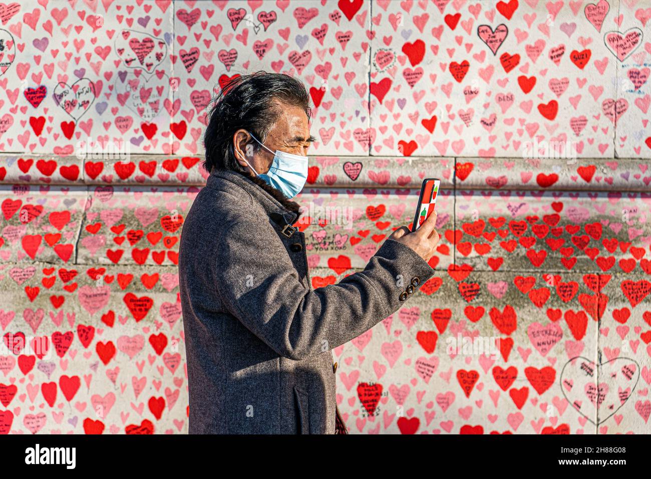 WESTMINSTER LONDRA, REGNO UNITO. 28 novembre 2021. La gente cammina oltre il muro del memoriale nazionale lungo il lungofiume del Tamigi in una luminosa domenica. Il governo ha annunciato misure più severe, tra cui l'obbligo di indossare maschere sui trasporti pubblici e nei negozi per fermare la diffusione della nuova variante sudafricana dopo che nel Regno Unito sono stati rilevati diversi casi del ceppo omicron. Credit: amer Ghazzal/Alamy Live News Foto Stock