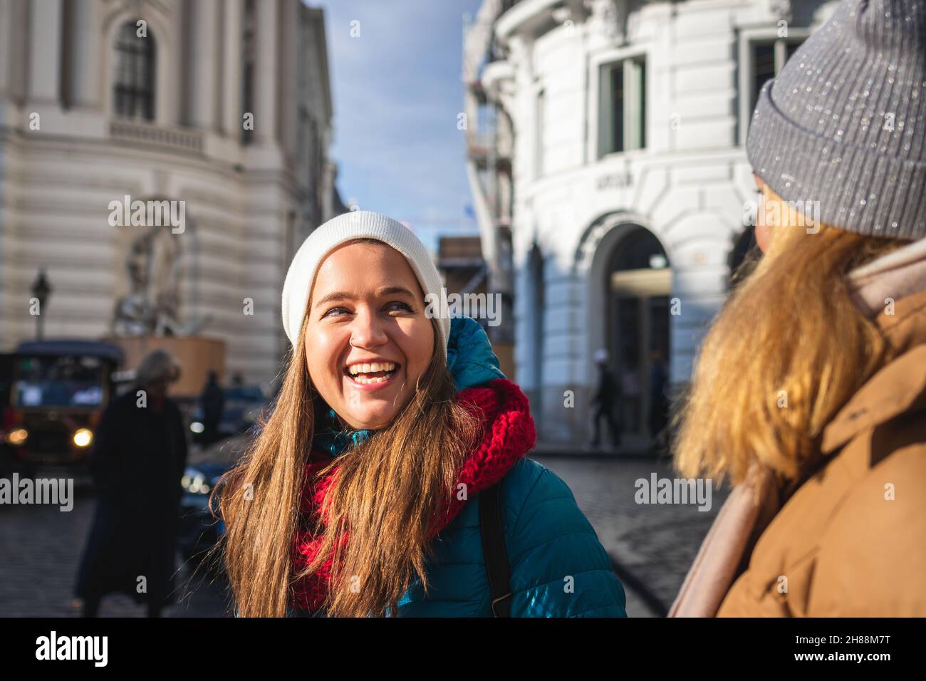Due donne che si divertono in città durante le vacanze a Vienna, Austria. Giovane donna che ride e la sua amica vicino al complesso di Hofburg. Felice sorridente turisti Foto Stock