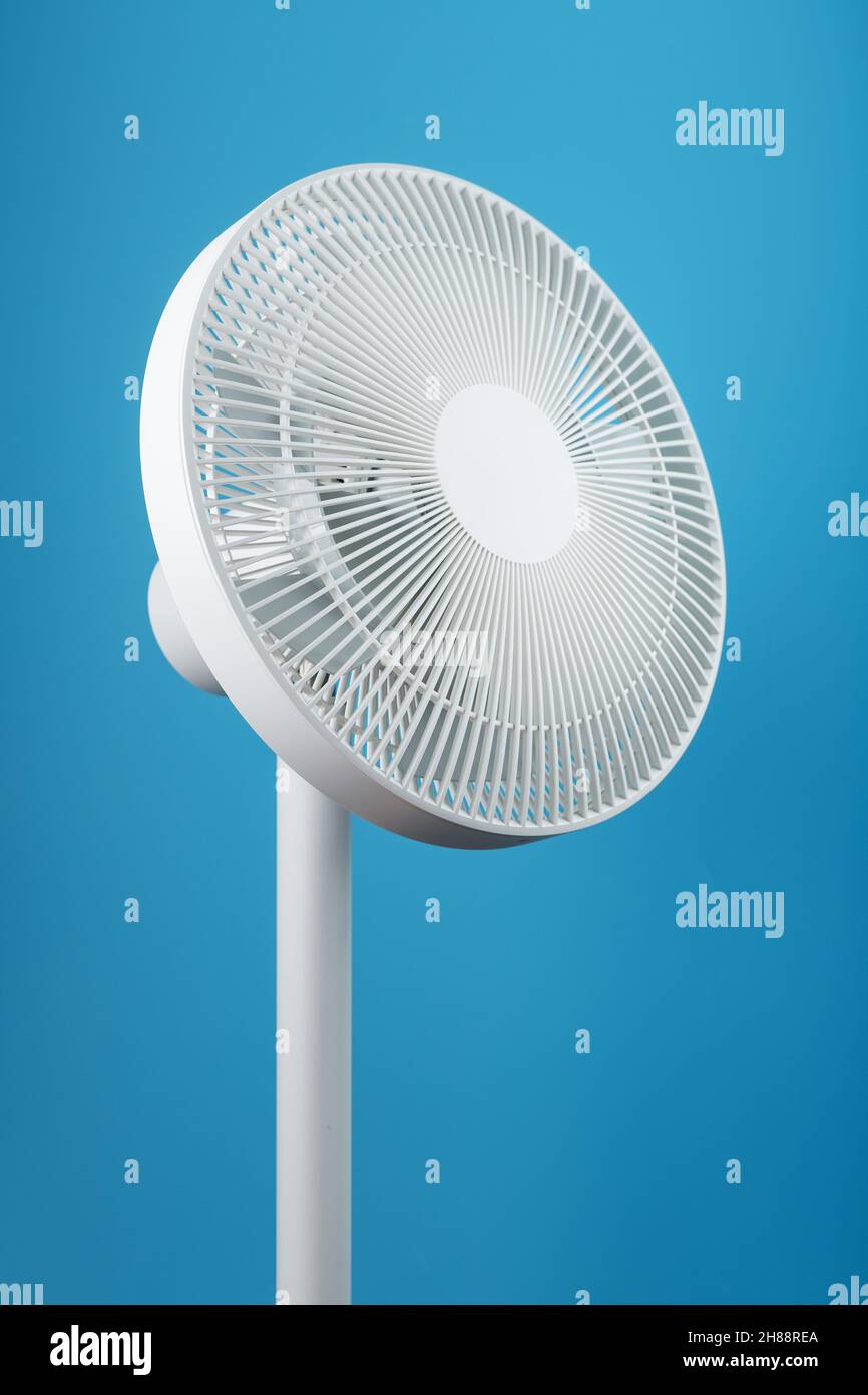 Un ventilatore elettrico bianco high-tech dal design moderno per raffreddare  la stanza su sfondo blu. Stile minimalista Foto stock - Alamy