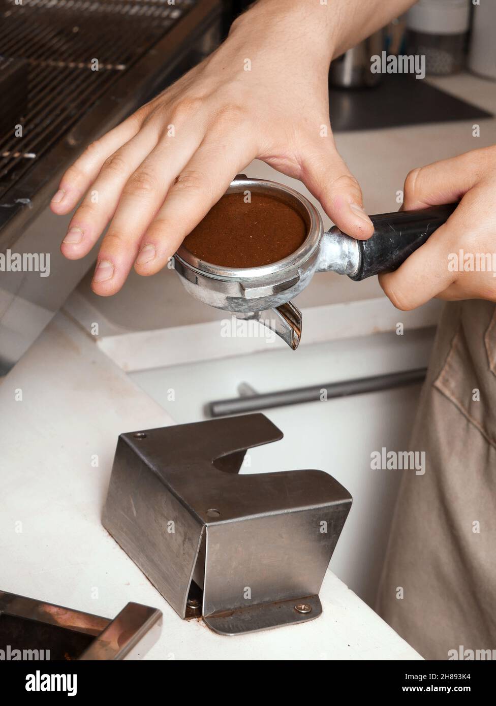 Barista che riempie il portafiltro con caffè appena macinato. Foto Stock