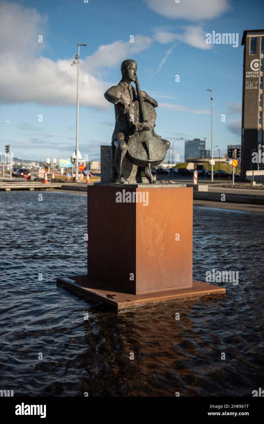 Statua del violoncellista danese Erling Blondal Bengtsson, dello scultore Olof Palsdottir, e la sala concerti di Harpa, Reykjavik, islanda Foto Stock