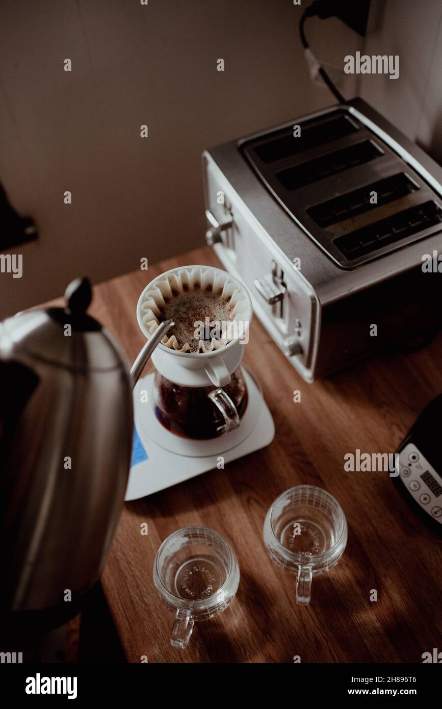 Versare l'acqua calda dal bollitore a collo d'oca nella macchina per caffè pour-over, estrazione lenta del caffè, caffè filtrato appena fatto, per preparare il caffè a casa Foto Stock