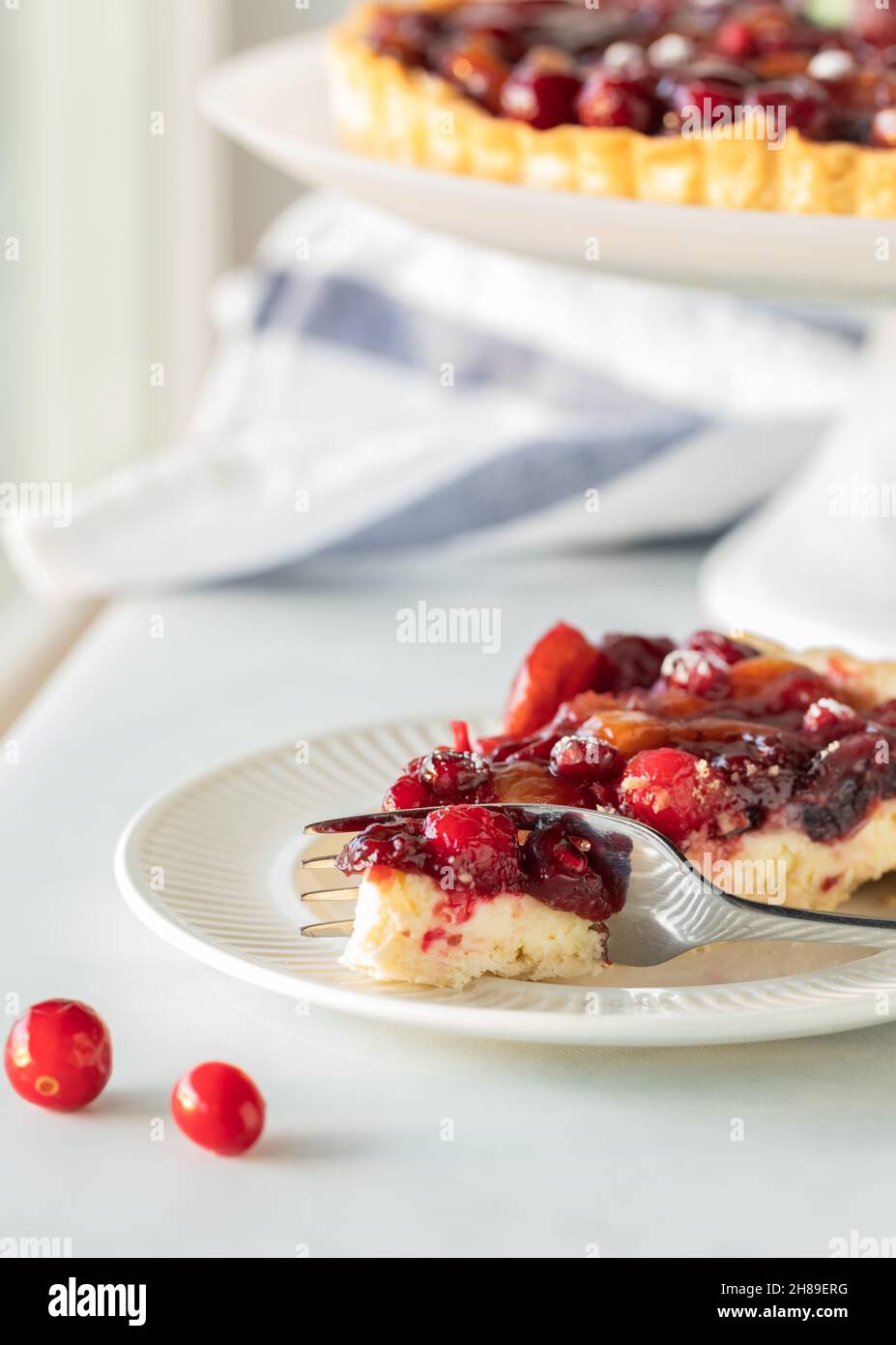 Primo piano di un pezzo di crostata di mirtilli con la torta completa dentro dietro. Foto Stock