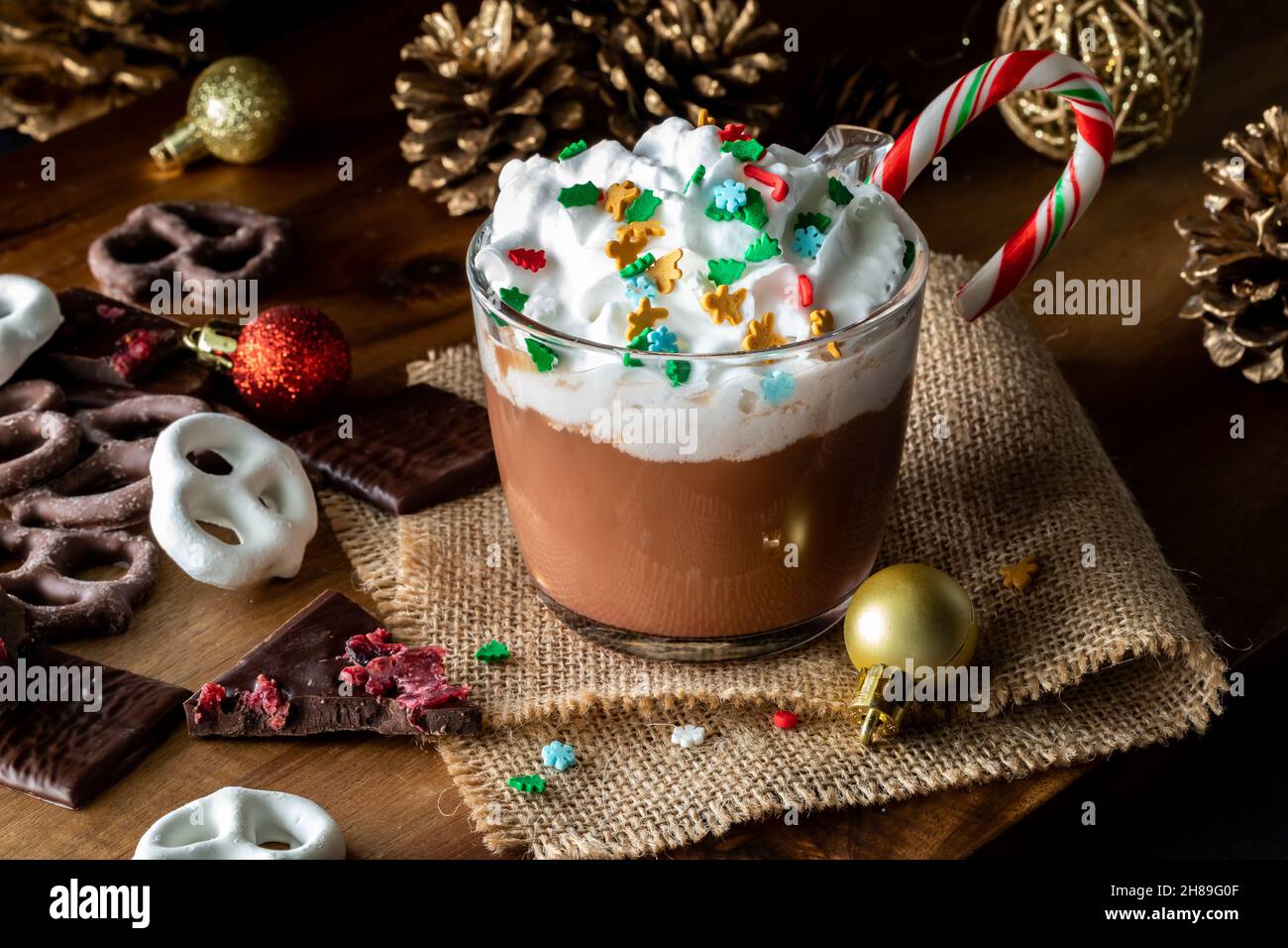 Scena festiva di cioccolata calda, panna a frusta e spolverini serviti con cioccolatini. Foto Stock