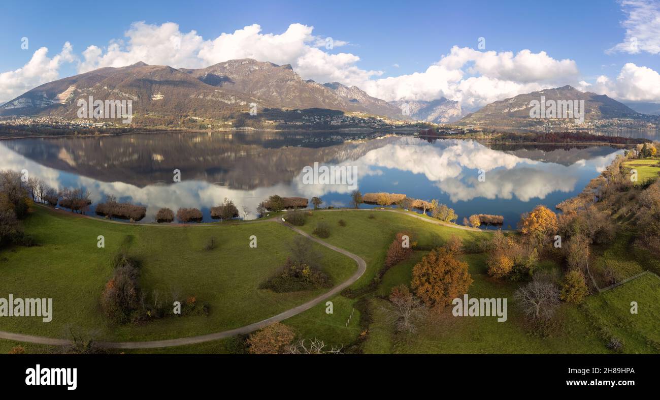 Veduta aerea di un lago alpino e delle montagne circostanti e vegetazioni riflesse in una giornata nuvolosa, Brianza, Lombardia, Italia Foto Stock