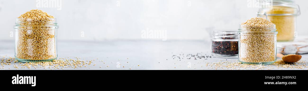 Grani di quinoa crudi in vaso. Cibo vegetariano sano su tavolo da cucina grigio. Messa a fuoco selettiva. Foto Stock