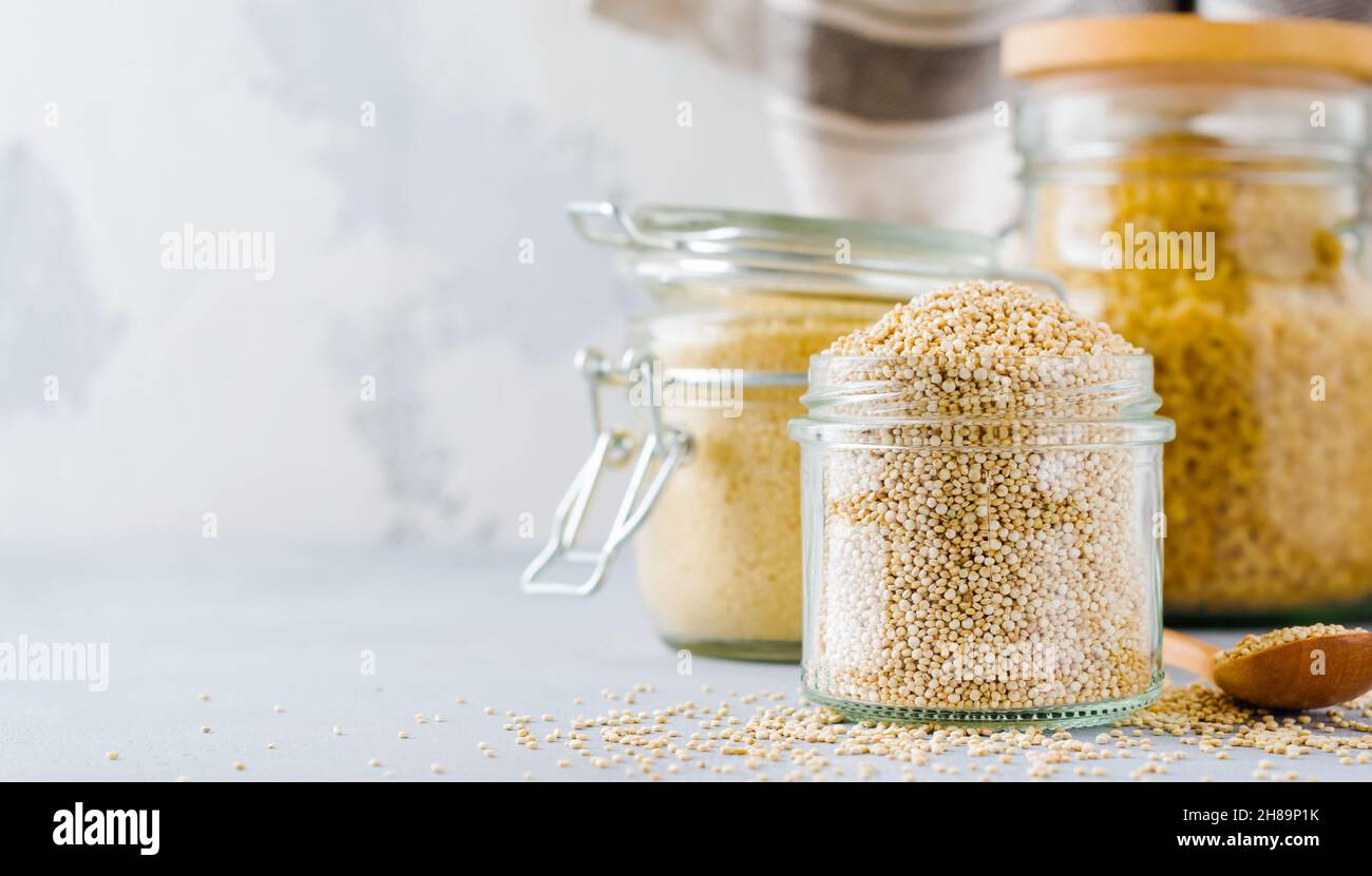 Grani di quinoa crudi in vaso. Cibo vegetariano sano su tavolo da cucina grigio. Messa a fuoco selettiva. Foto Stock