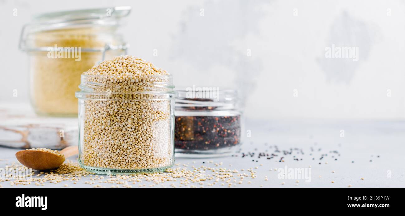 Grani di quinoa crudi in vaso. Cibo vegetariano sano su tavolo da cucina grigio. Messa a fuoco selettiva. Foto Stock