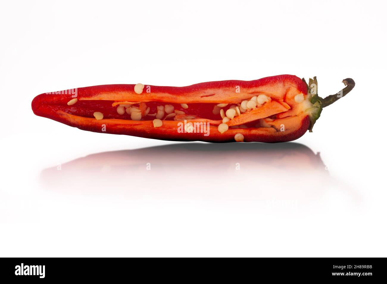 Peperoncino rosso caldo tagliato a fette a metà da vicino isolato su sfondo bianco con riflessi Foto Stock