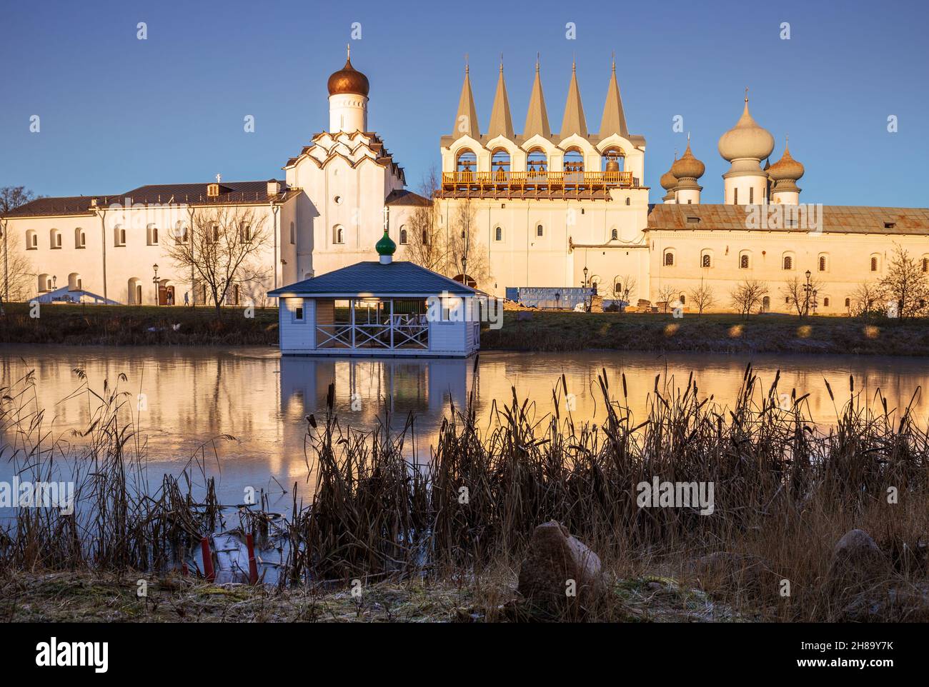 Monastero dell'Assunzione di Tikhvin, campanile e chiesa sulla riva di un lago ghiacciato. Regione di Leningrad, Russia Foto Stock