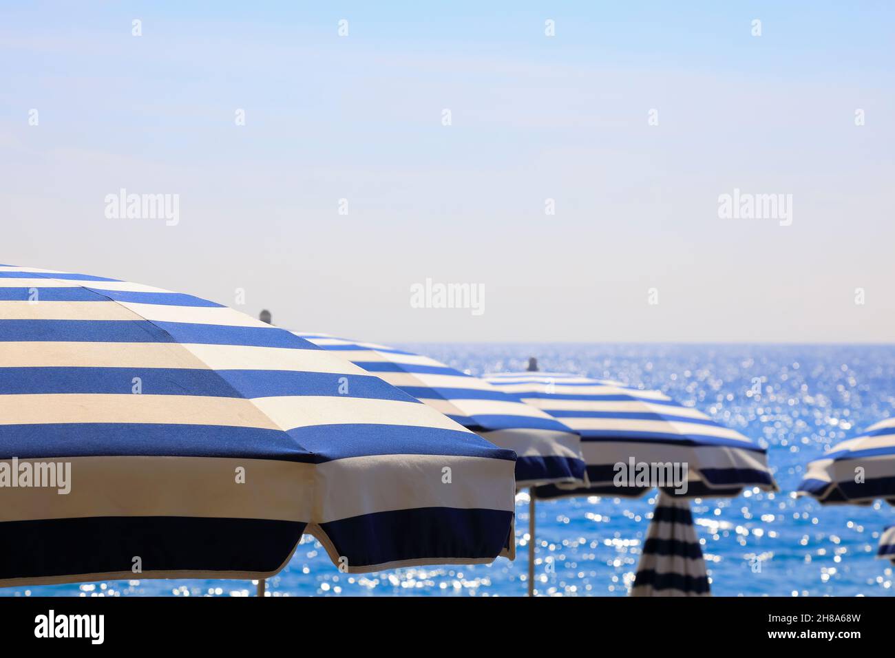 Ombrelloni in tessuto a strisce blu e bianche sono visibili dal Mediterraneo a Nizza, Francia. Foto Stock