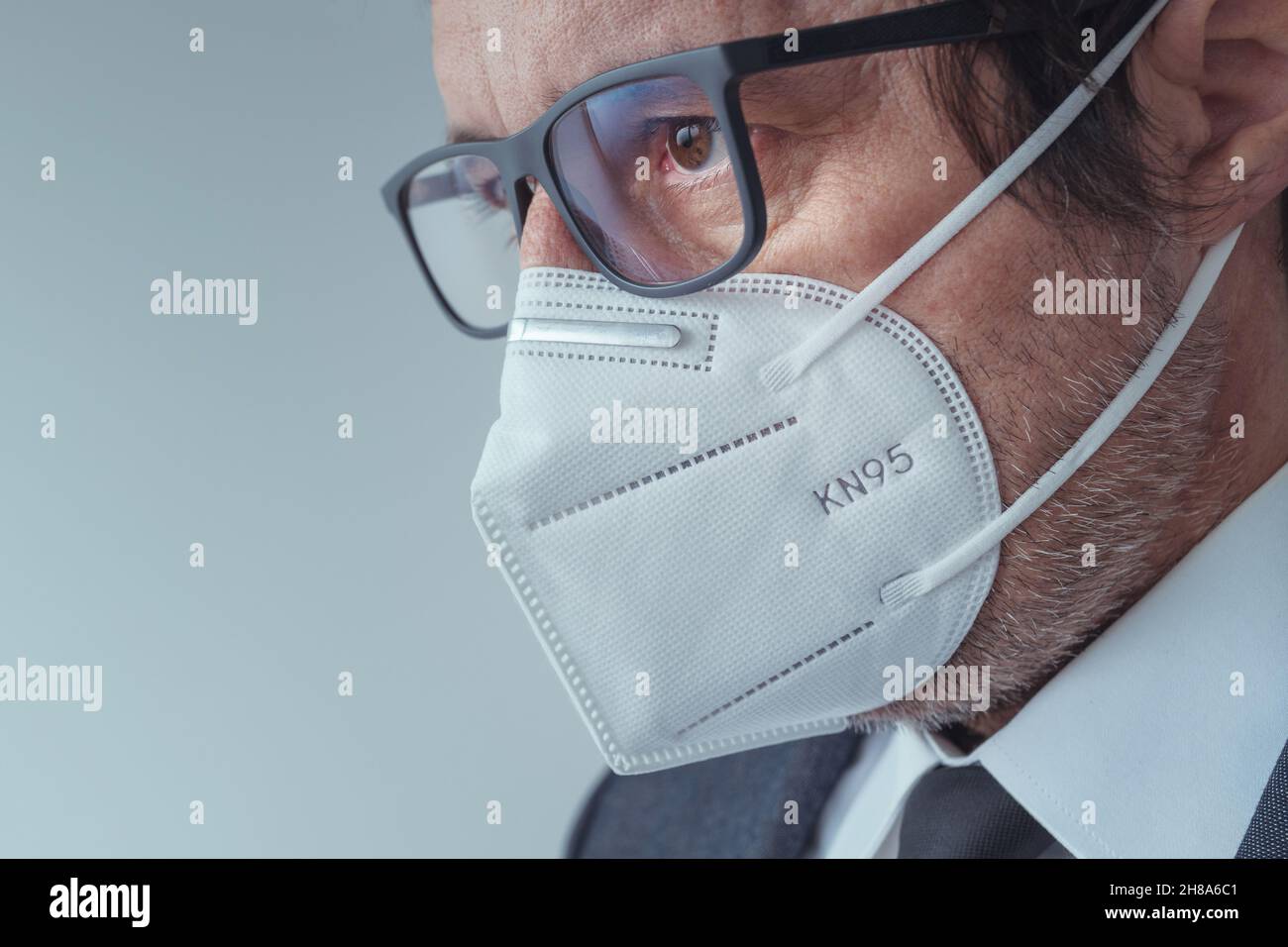 Elegante uomo d'affari che indossa maschera respiratoria protettiva KN95 durante le pandemie di Covid-19, fuoco selettivo Foto Stock