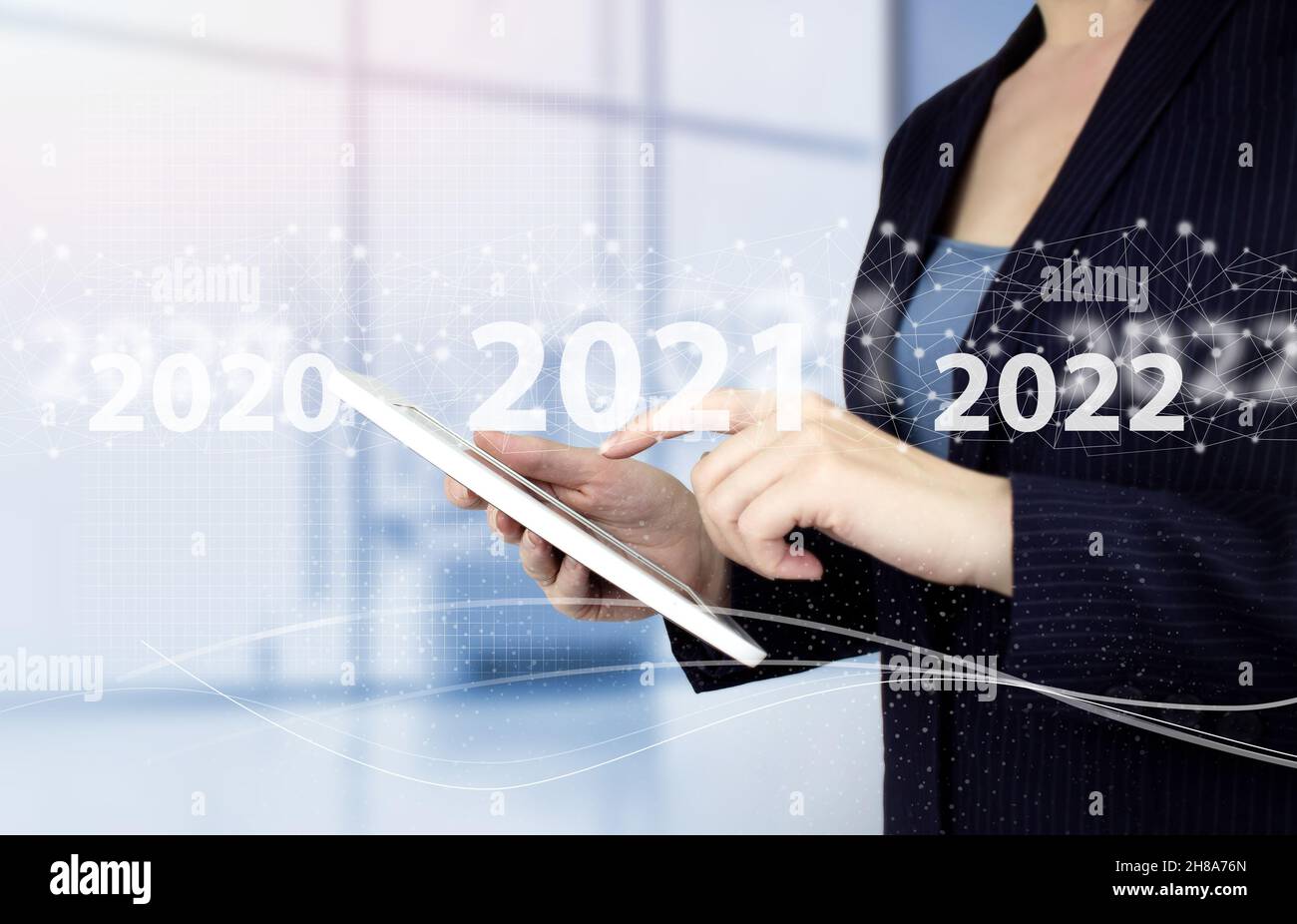 Anno di carico dal 2021 al 2022. Inizia concetto. Toccare a mano il tablet bianco con il segno ologramma digitale 2021 su sfondo sfocato chiaro. Benvenuto anno 2022. Busi Foto Stock