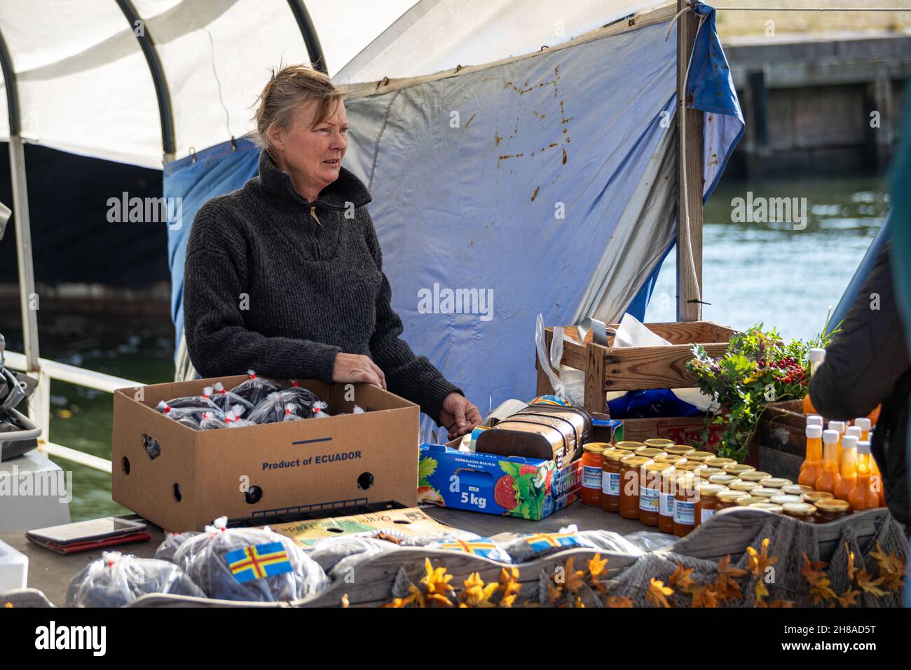 Donna che vende pane nero e prodotti connessi al mare ​​buckthorn dalla stalla di Stadin silakkamarkkkkinat o Helsink Baltic Herring Market, Finlandia Foto Stock