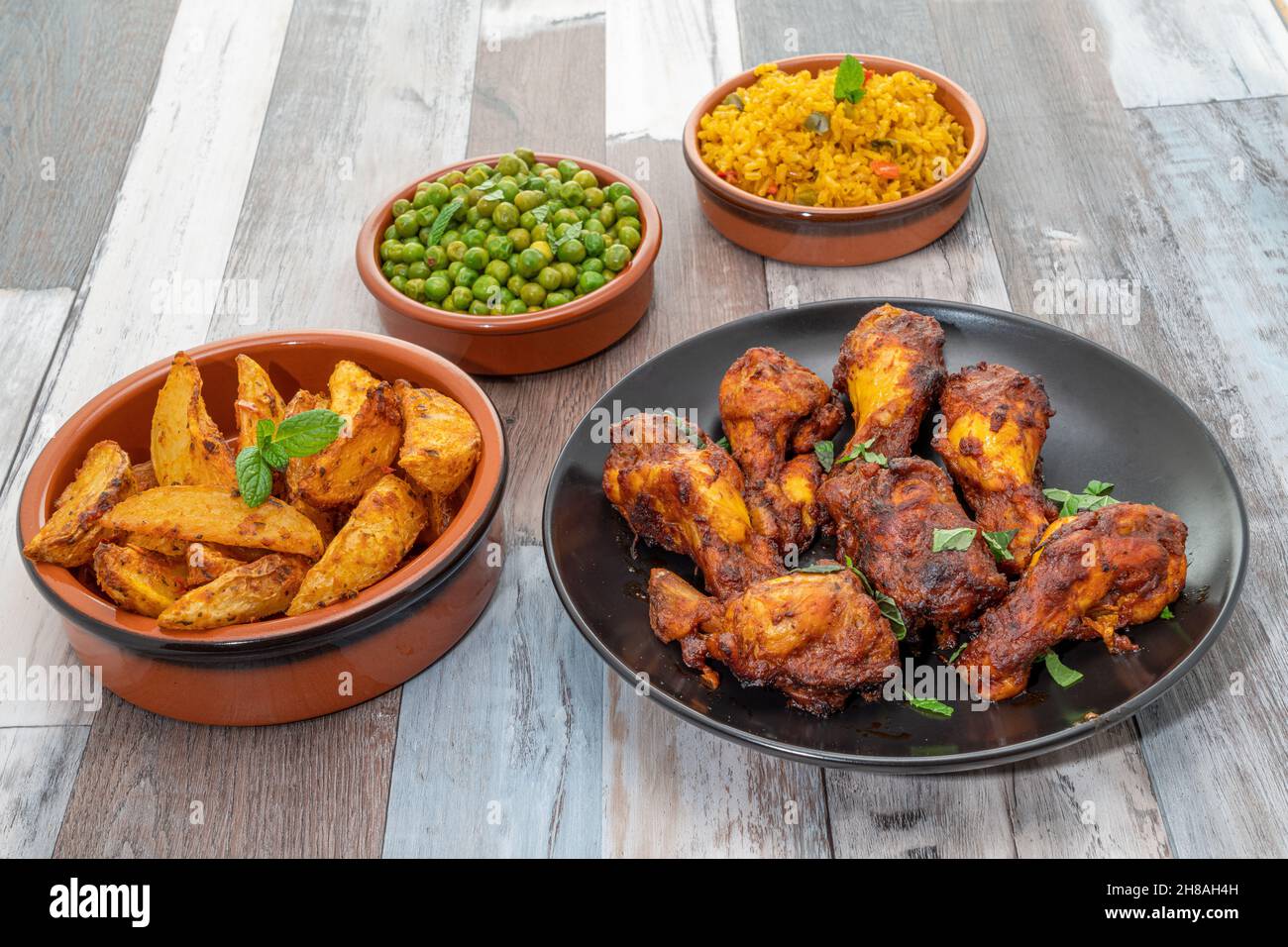 Pasto con ali di pollo peri-Peri con spicchi piccanti, piselli e riso Foto Stock