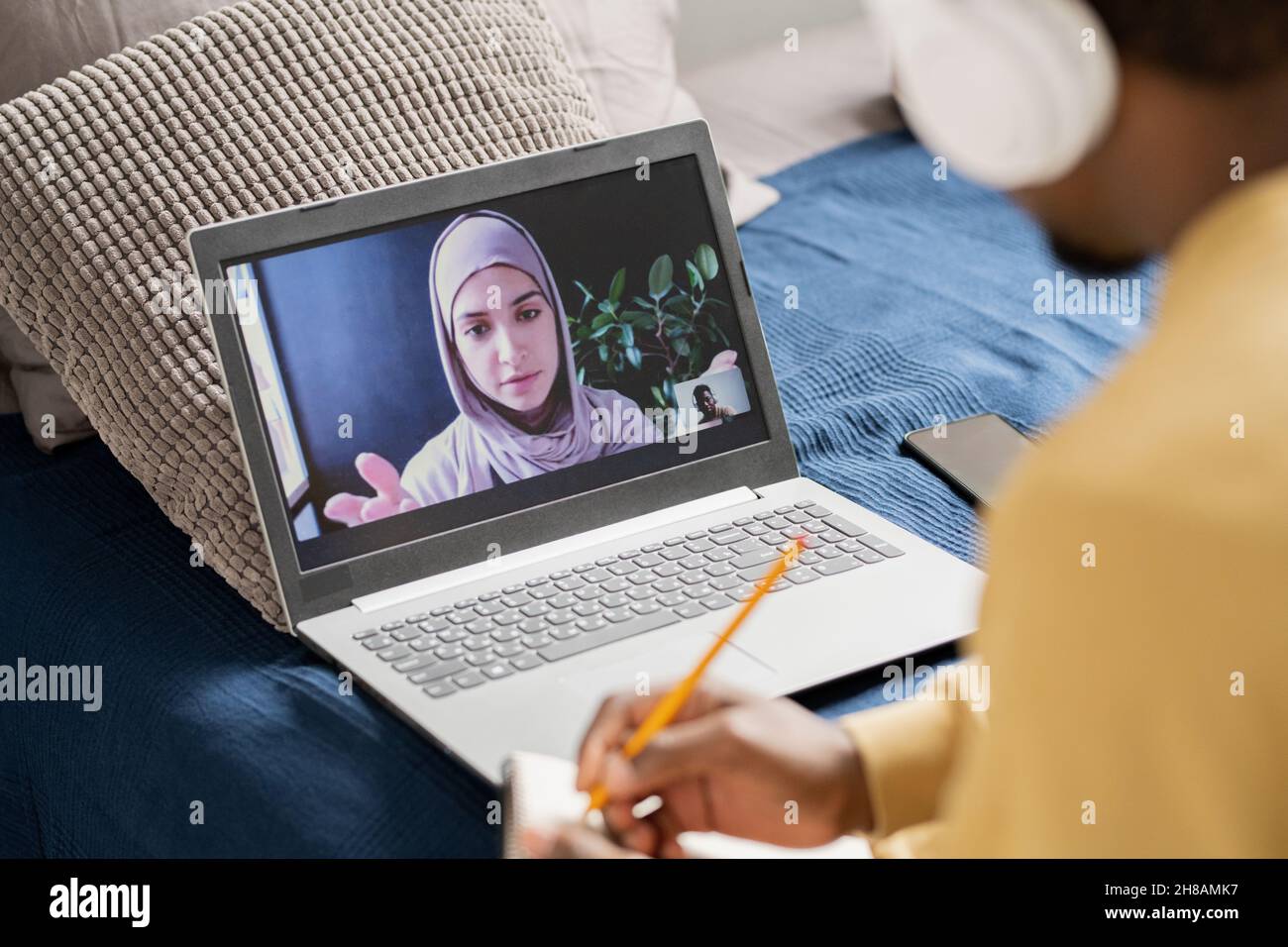 Giovane insegnante fiducioso sullo schermo del laptop che guarda lo studente africano mentre lo spiega l'argomento della lezione online Foto Stock